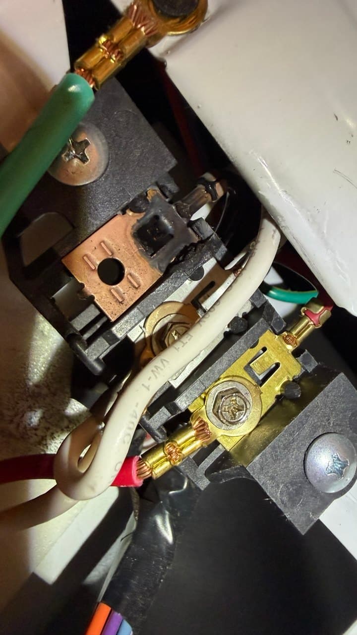 Close-up of an electrical terminal block showing significant charring and burn damage from overheating.